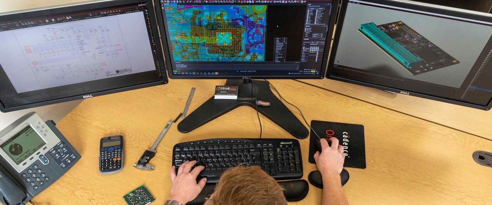 PCB design review desk | GlobalWin Workstation with circuit-design screens, a keyboard and sample circuit boards