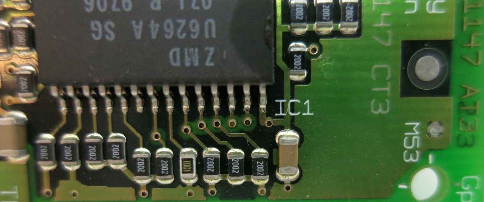 Close-up of surface-mount component leads and small passive components on a circuit board